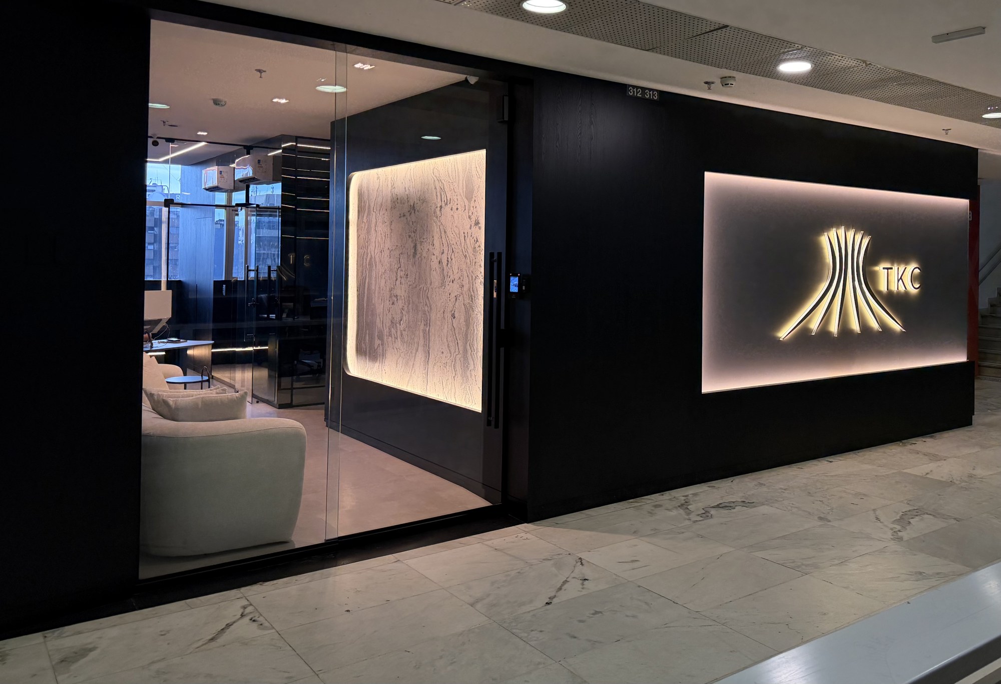 Entrada da sede da TKC com logotipo iluminado